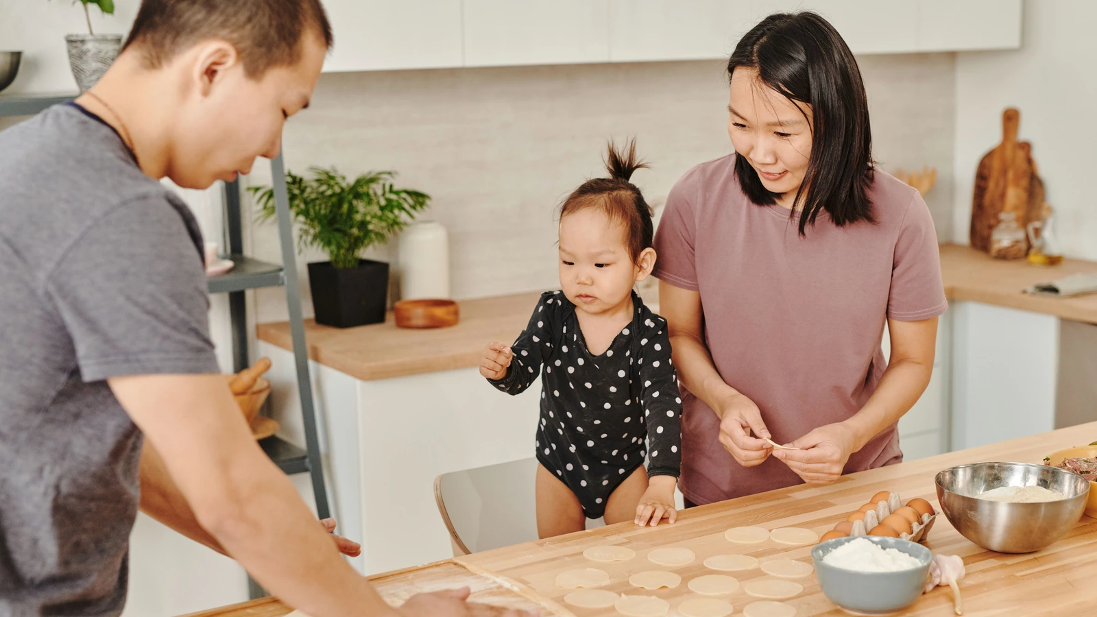 Family making dumplings together around a table at home.