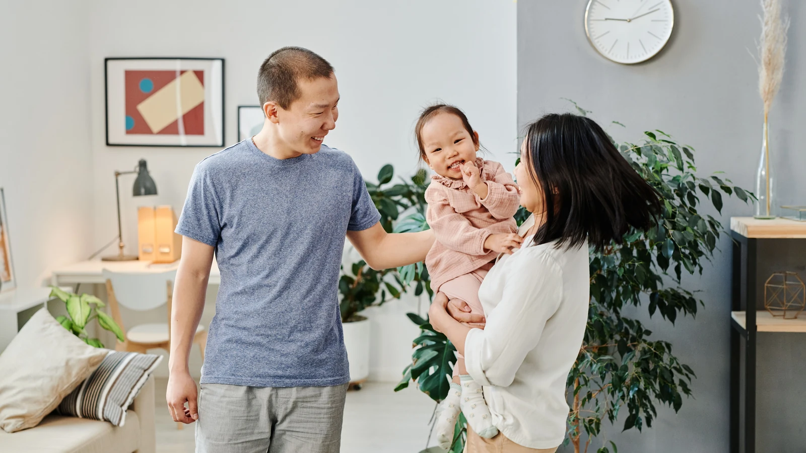 Family smiling together beside a large houseplant indoors.