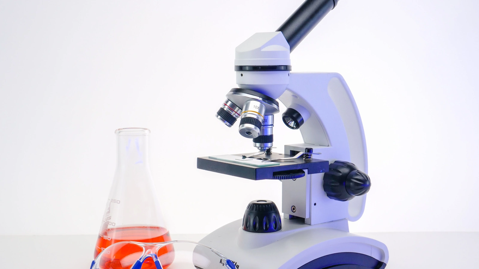 Microscope and laboratory glassware on a workbench.