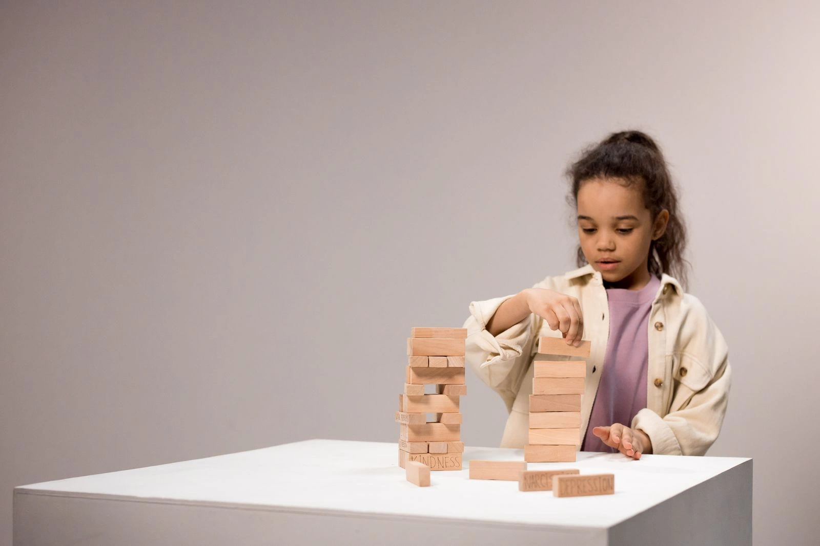 A young girl concentrating on stacking wooden blocks at a table